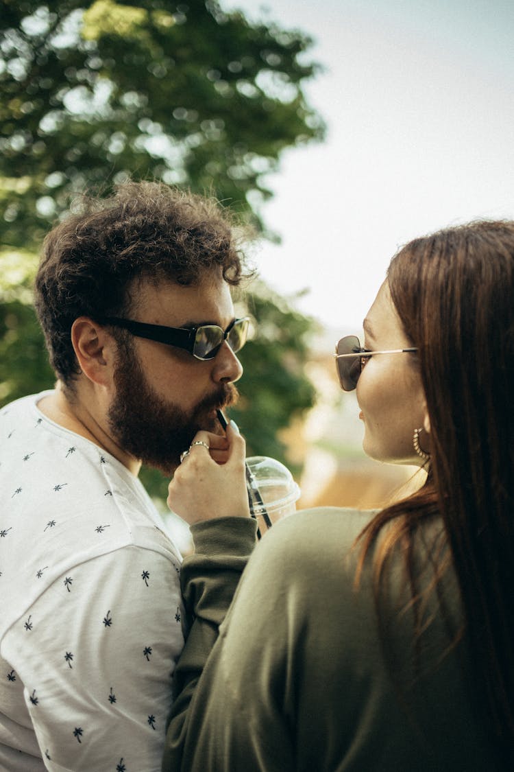 Bearded Man Drinking From A Straw Beside A Woman