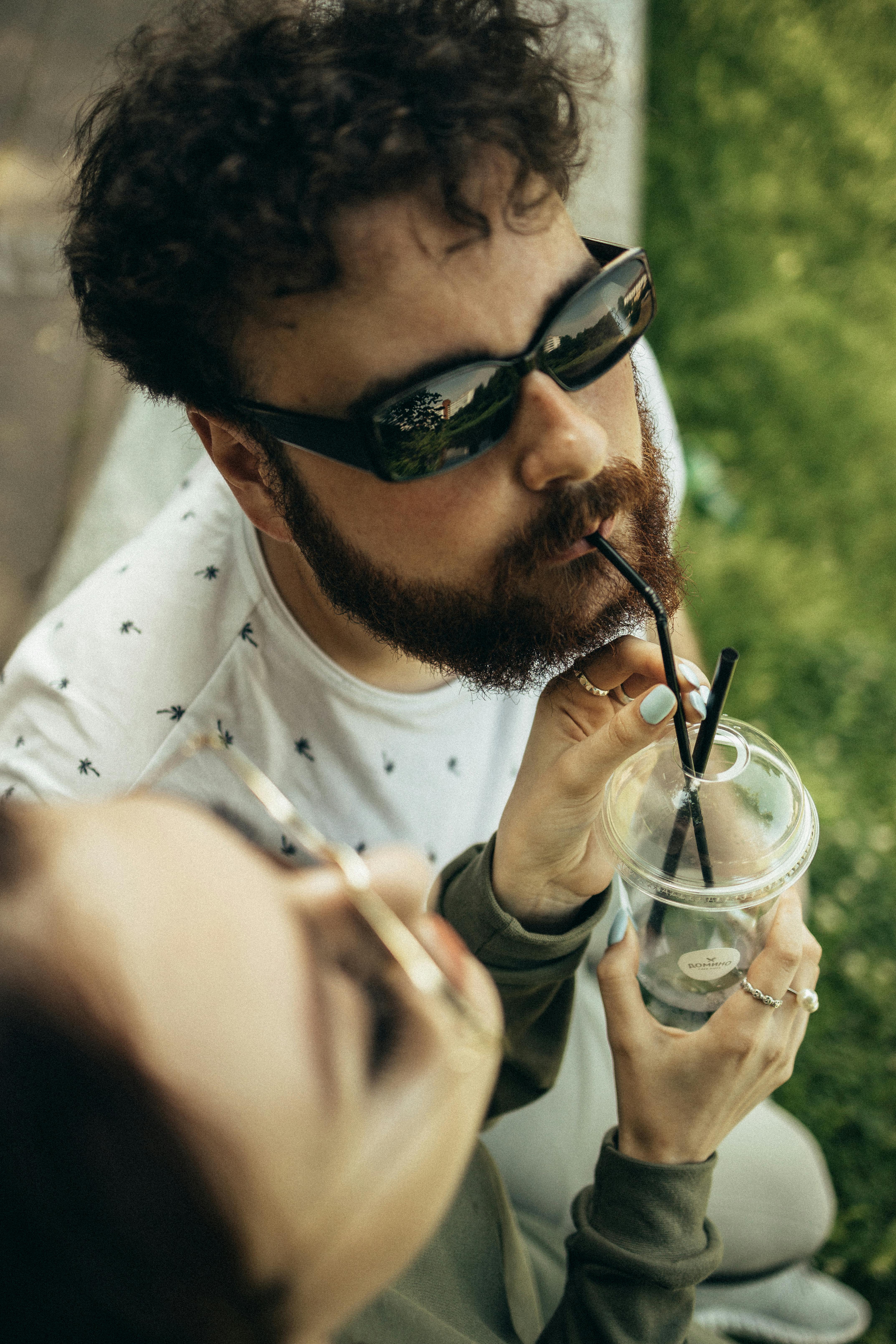 man in white crew neck shirt holding clear plastic cup