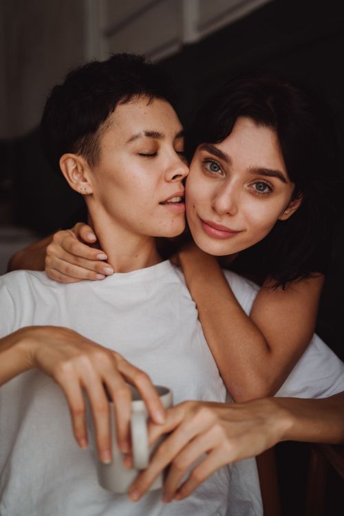 Free Close-up portrait of a loving lesbian couple embracing with warmth and affection indoors. Stock Photo