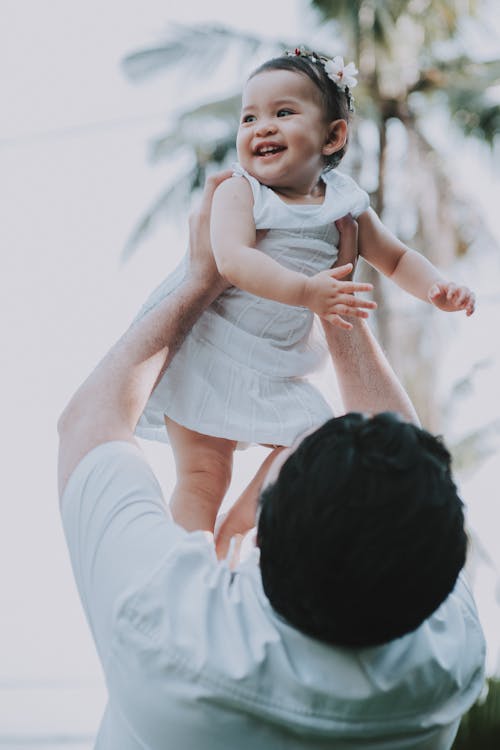 Free Man Carrying a Baby Girl in White Dress Stock Photo