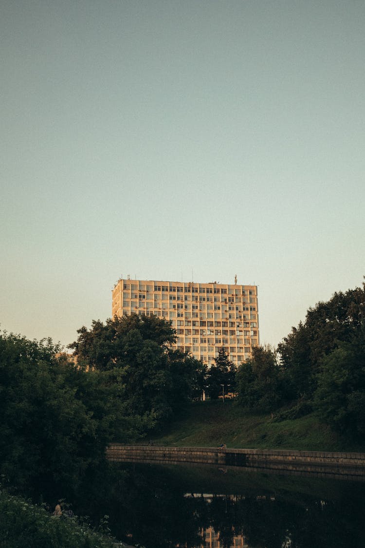 Block In A Post-soviet Architecture Style Peeking From Behind The Trees In City 