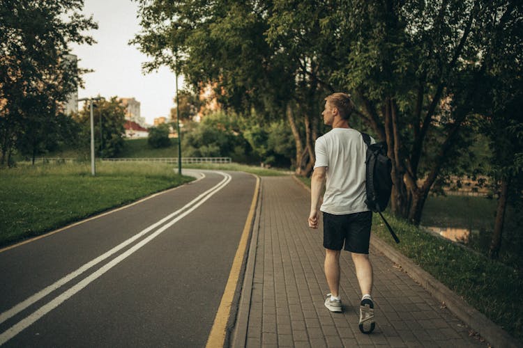 A Man In White Shirt Walking On Sidewalk