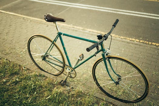 A classic green bicycle parked on a sidewalk beside a street during the day.