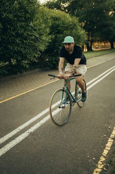 白天，一名男子在公园小路上悠闲地骑着自行车