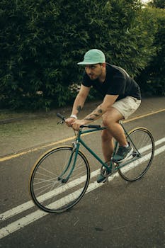A man rides a bike on a tree-lined path in the city, showcasing urban cycling.