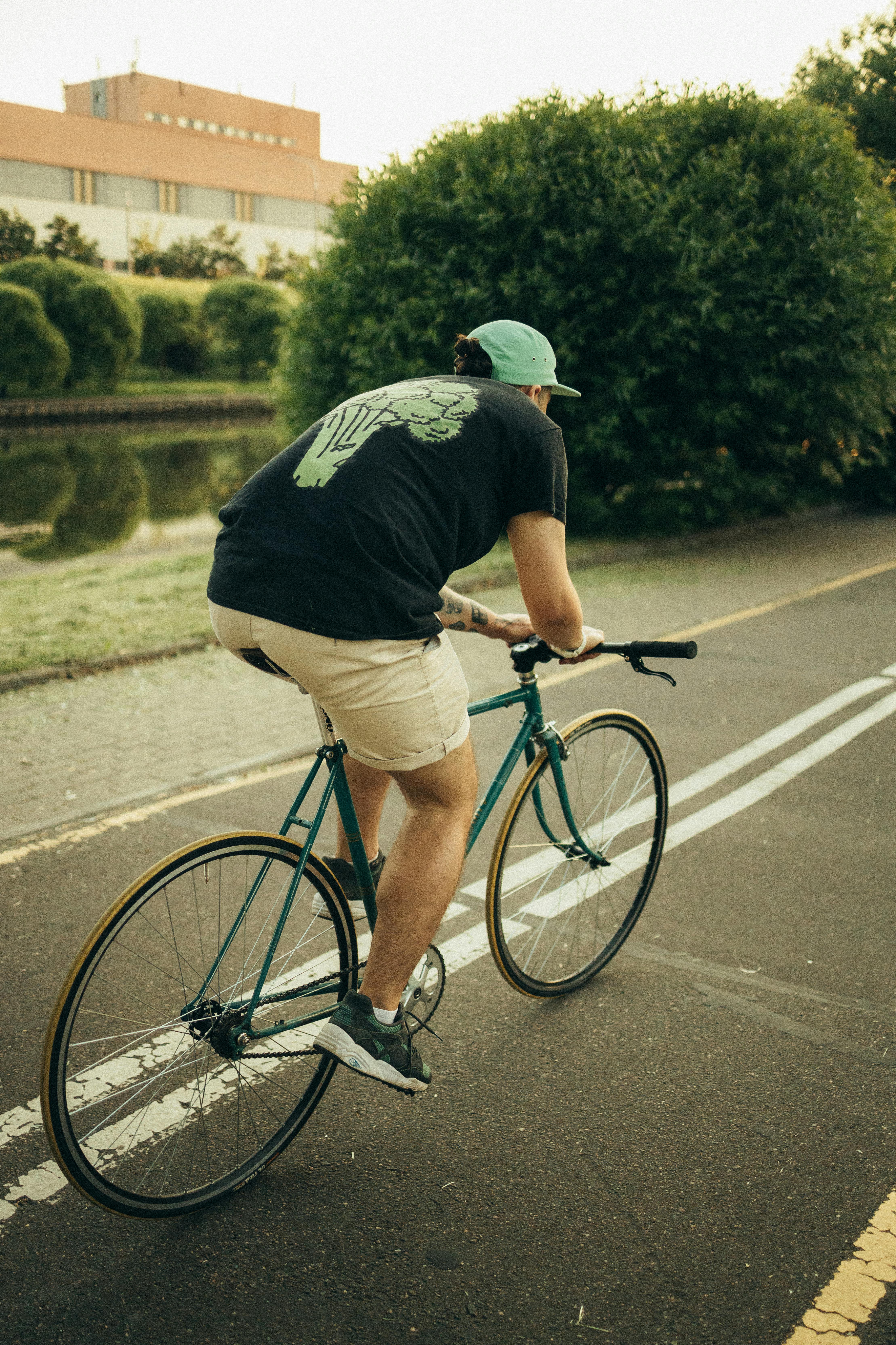 Man in Black T-shirt Riding on Bicycle on Road