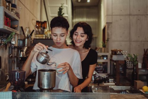 Free A smiling couple pours coffee in a cozy kitchen, capturing a moment of warmth and connection. Stock Photo