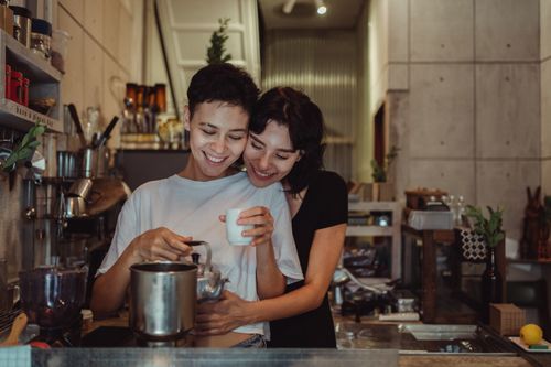 Free A happy couple shares a warm embrace while preparing coffee in a stylish kitchen. Stock Photo