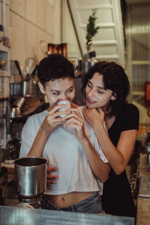 Free Two women share a tender moment in a cozy cafe, enjoying a warm cup of coffee. Stock Photo