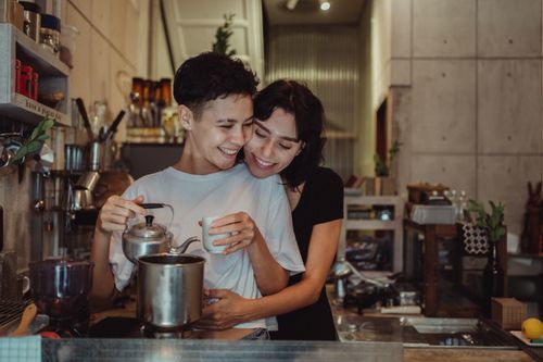 Free Joyful couple bonding in a cozy kitchen, sharing a warm moment over coffee. Stock Photo