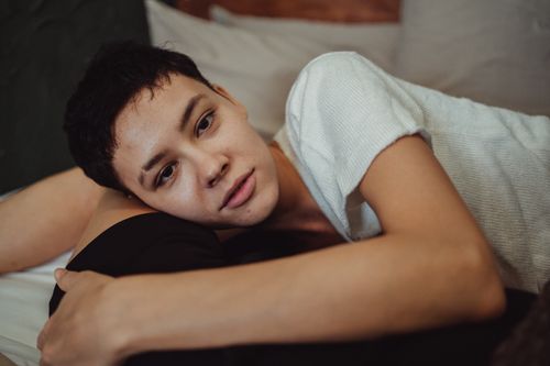 Free A serene moment of a young woman lying on a bed, embracing comfort and relaxation indoors. Stock Photo