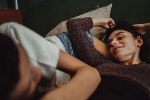 Free Two women lying down, enjoying a moment of relaxation and intimacy, with warm tones creating a cozy feel. Stock Photo