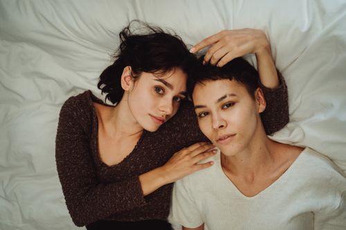 Free A tender moment between two women lying together on a bed, showcasing intimacy and connection. Stock Photo