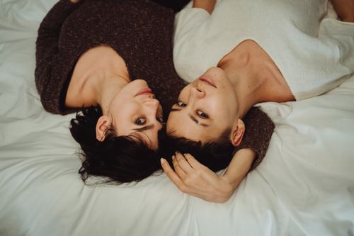 Free A loving couple lying together on a bed, embracing and showing affection. Stock Photo