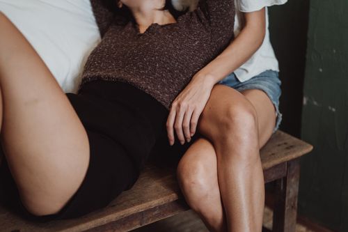 Free Two women relaxing closely on a wooden bench, showcasing intimacy and friendship. Stock Photo