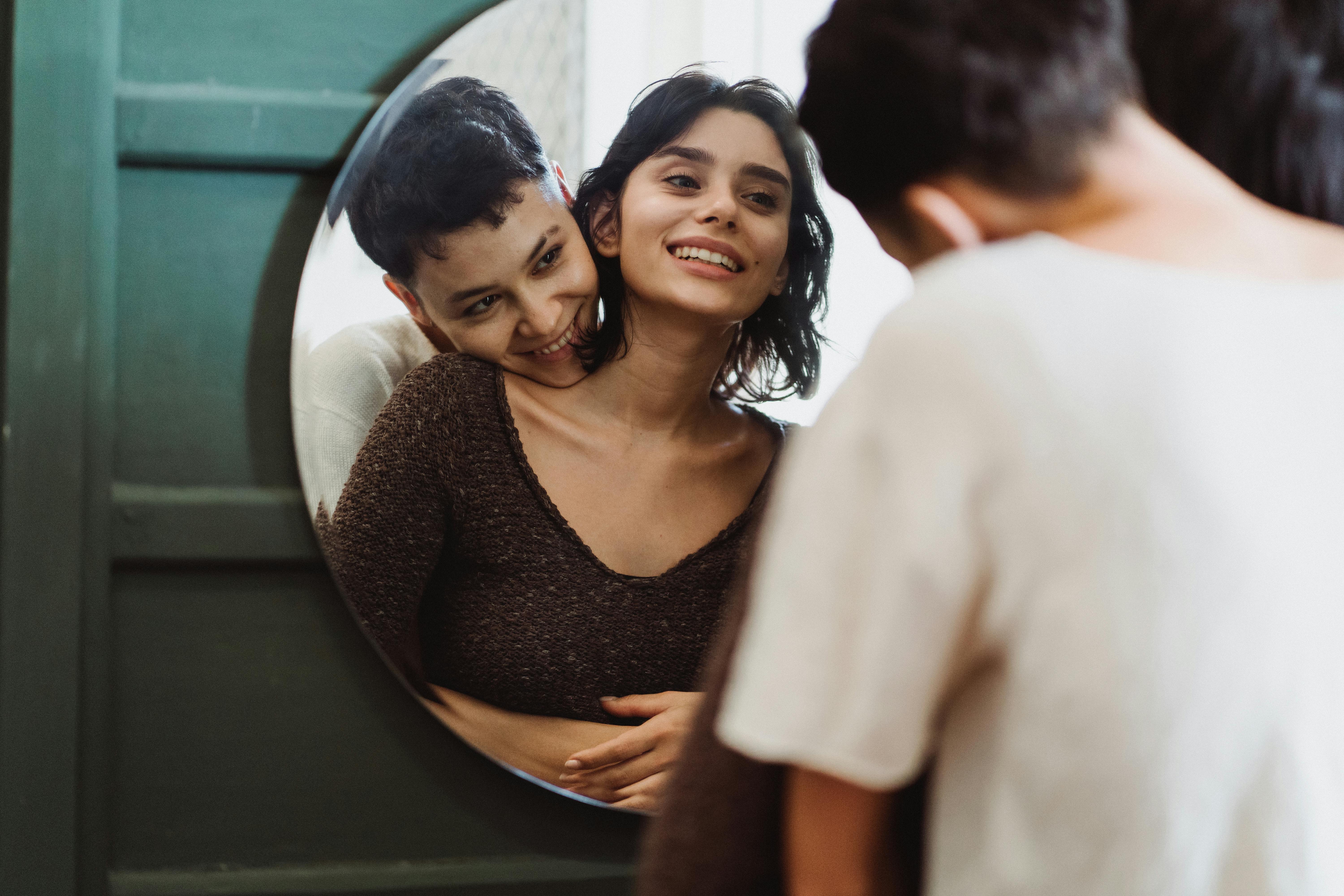 two women looking at themselves in a mirror