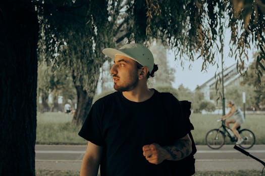 一名男子在阳光明媚的公园里，漫步于树下，捕捉着宁静的夏日时光