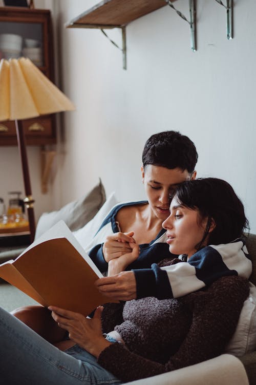 Free Two Women Cuddling and Reading a Book Stock Photo