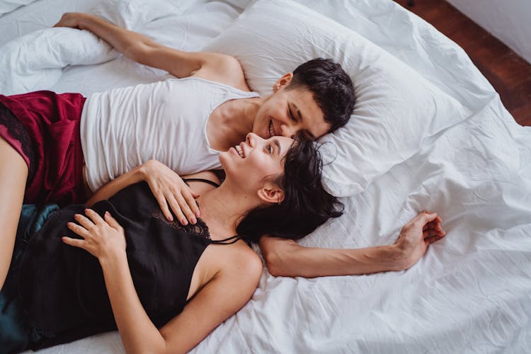 Happy Couple Lying And Laughing In Bed