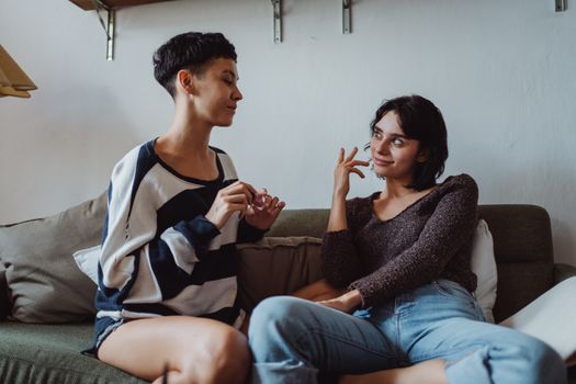 Two women having a relaxed conversation on a couch indoors.