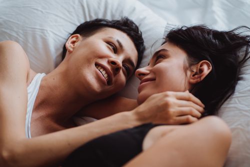 Free A loving couple sharing a tender moment in bed, embracing and smiling at each other. Stock Photo