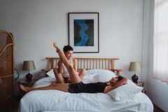 Two women having fun and laughing together in a cozy bedroom setting.