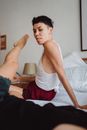 Man in White Tank Top Sitting on Bed