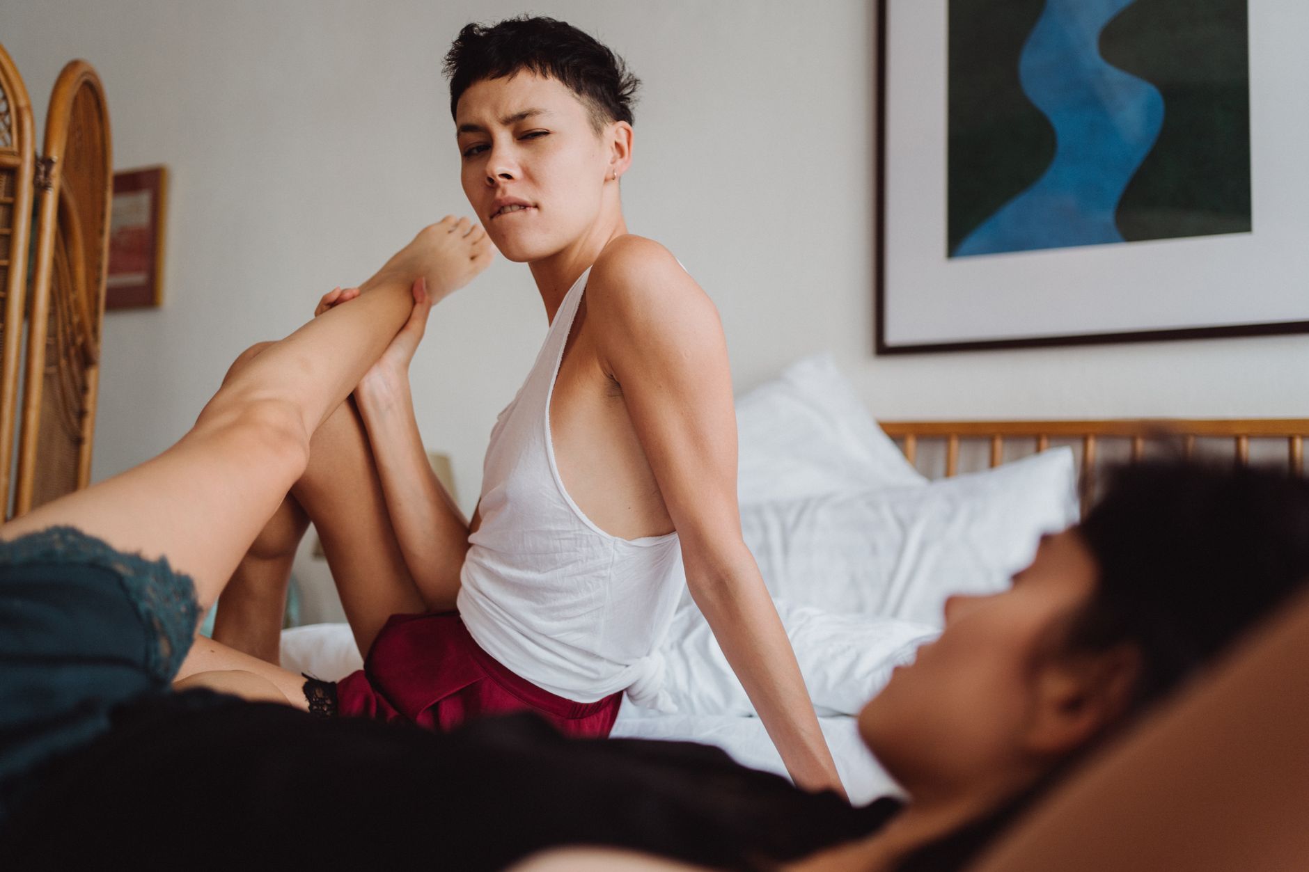 Two women in intimate setting enjoying a cozy moment in a bedroom, reflecting love and relaxation.