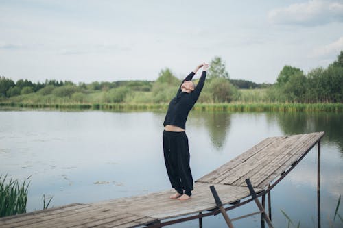 Men Stretching While Standing on a Wooden Pier 