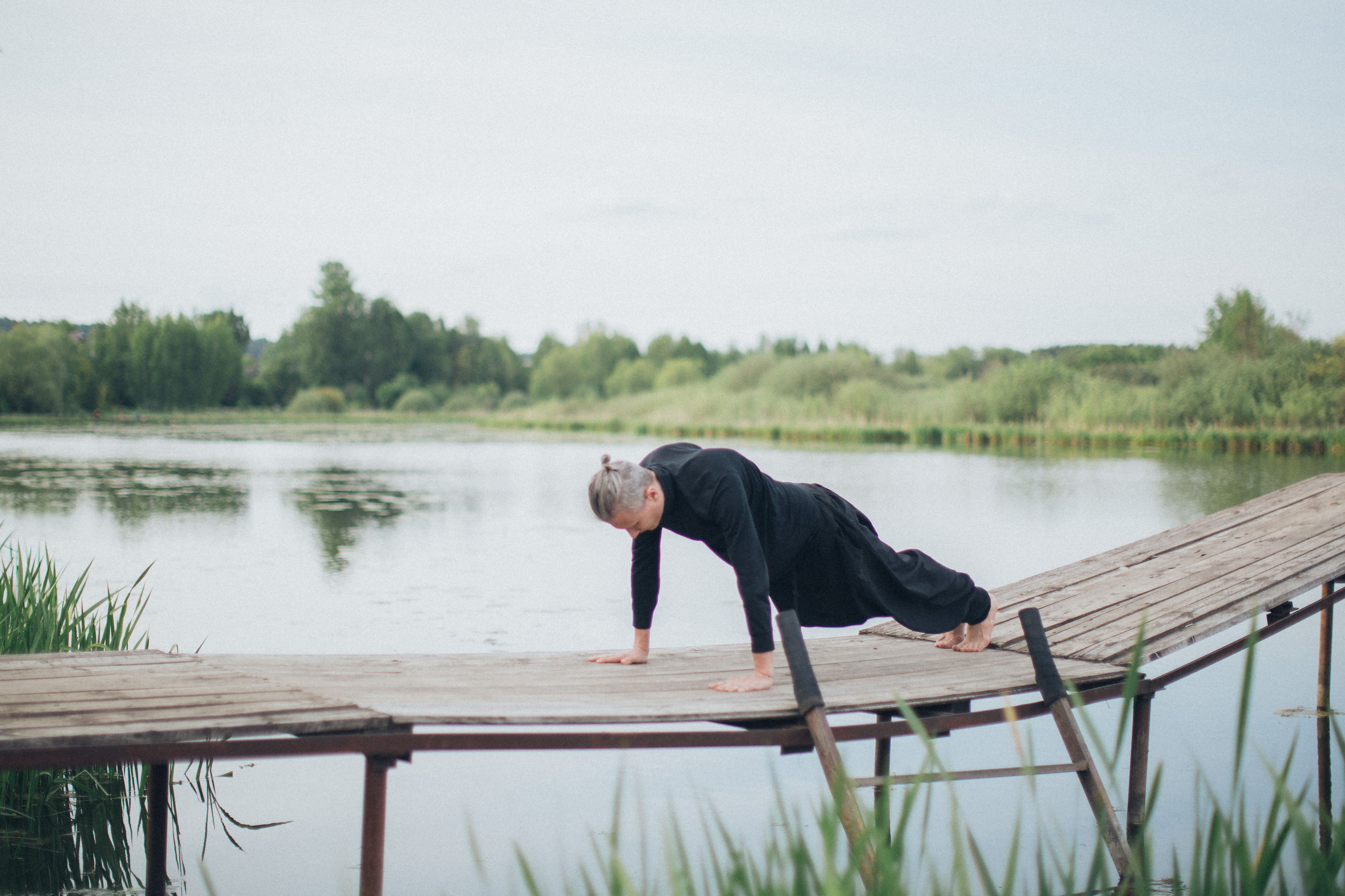 A man exercises on a wooden bridge beside a serene lake, embracing a healthy lifestyle.