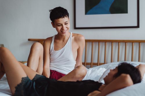 Free A joyful couple relaxing and smiling in a cozy bedroom setting, capturing intimate togetherness. Stock Photo