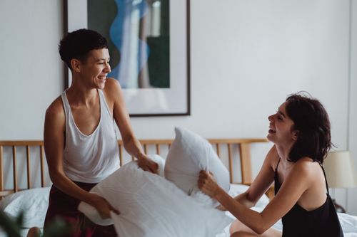 Free Happy couple having a pillow fight in a cozy bedroom, sharing laughter and love. Stock Photo
