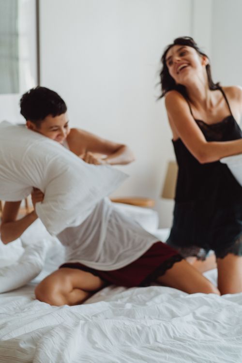 Free A couple enjoying a playful pillow fight, showcasing joy and affection indoors. Stock Photo