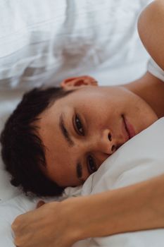 一位短发女士面带微笑，在宁静的室内枕着枕头放松身心