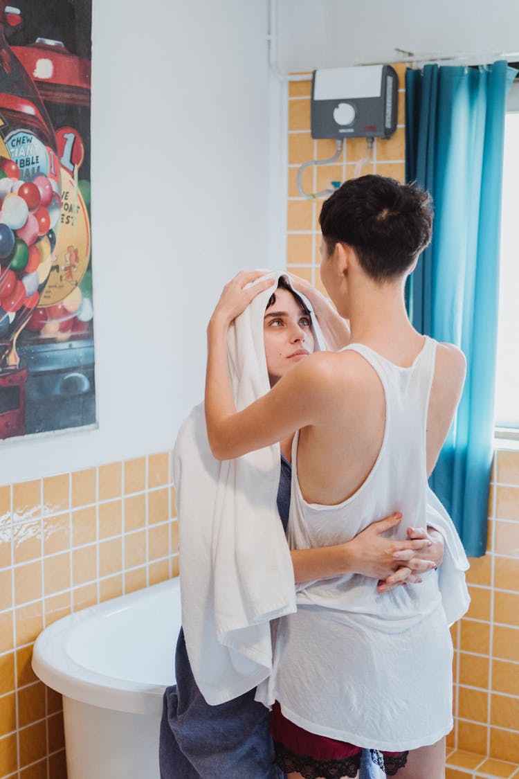 Woman Drying Another Woman's Hair With A Towel