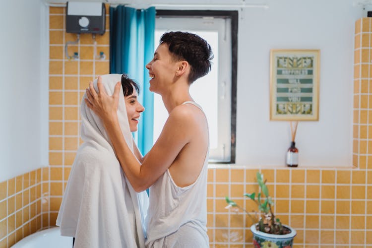 Woman Drying Another Woman's Hair With A Towel