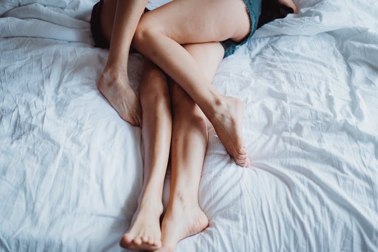 Close-up On Womens Legs Intertwined In Bed 