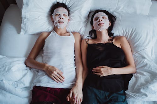 Women Holding Hands in Bed