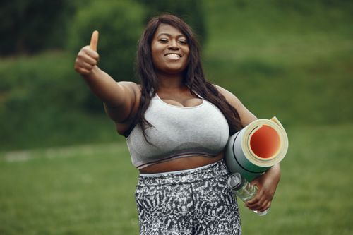 Free Happy woman in sportswear with yoga mat showing thumbs up outdoors. Perfect for fitness and lifestyle content. Stock Photo