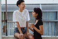 两个女人在阳台上笑着一起喝咖啡，洋溢着幸福与亲密