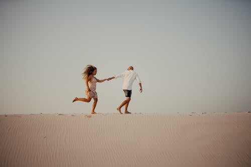 Foto profissional grátis de andando, casal, duna de areia
