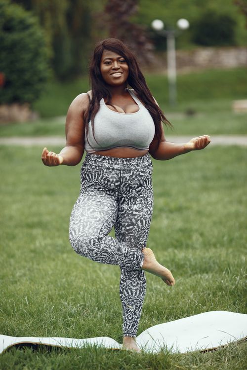 Free African American woman practicing yoga in a grassy field, promoting wellness and a healthy lifestyle. Stock Photo