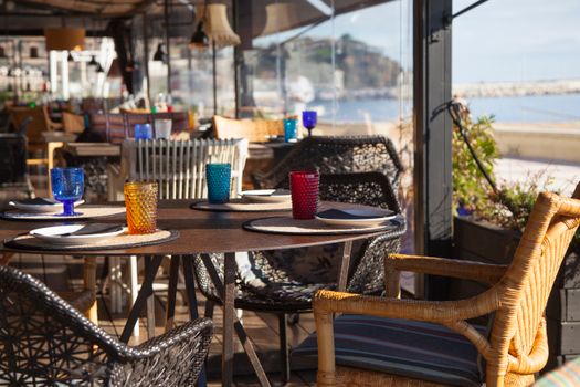 Elegant seaside restaurant with a stunning terrace view and vibrant glassware.