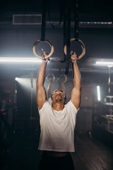 Athletic man working out with gymnastic rings indoors, showcasing strength and fitness.