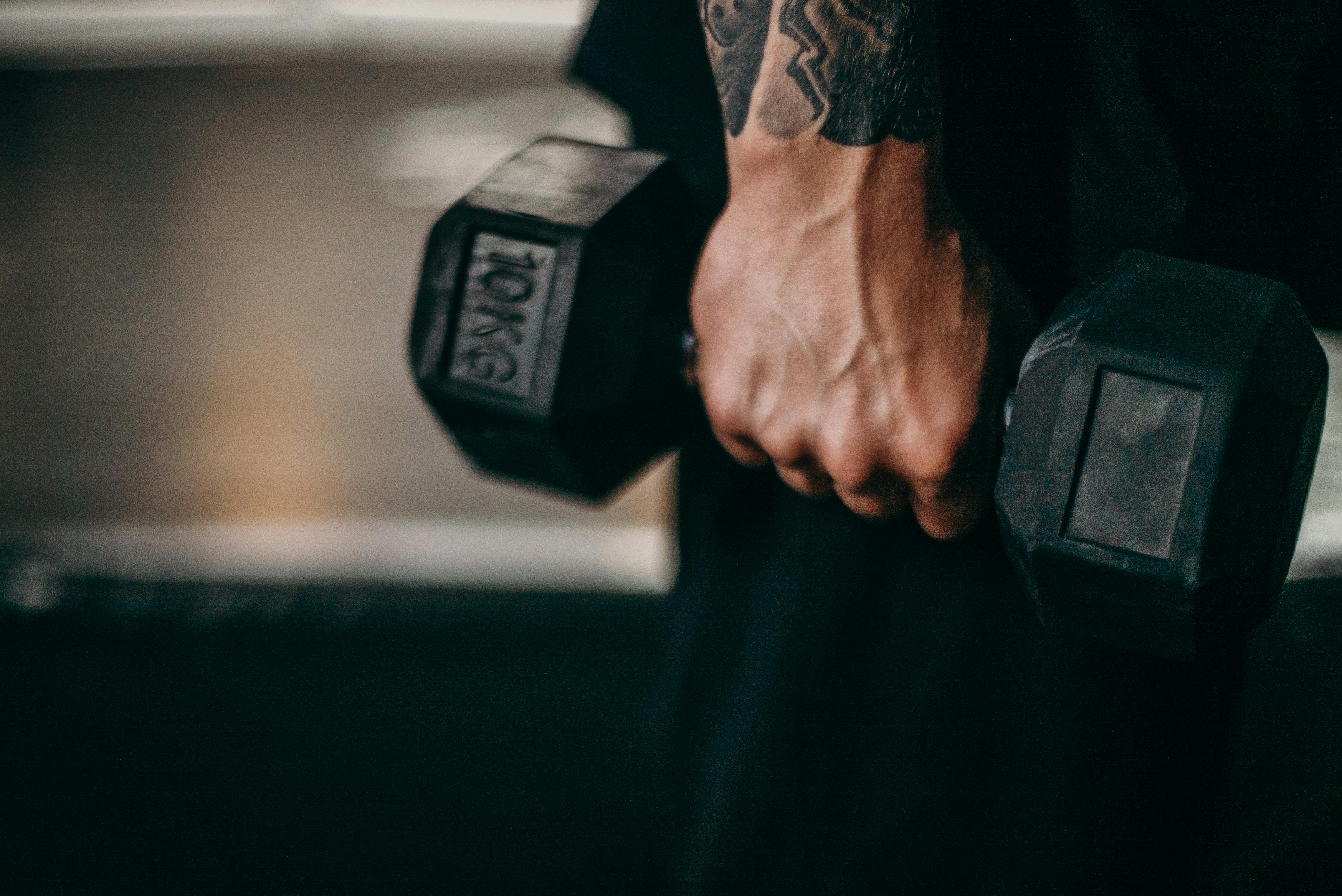 person holding black dumbbell with black tattoo