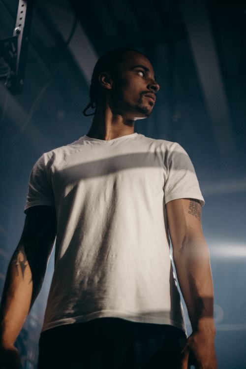 Free Muscular man in a white t-shirt standing confidently indoors under dramatic lighting. Stock Photo