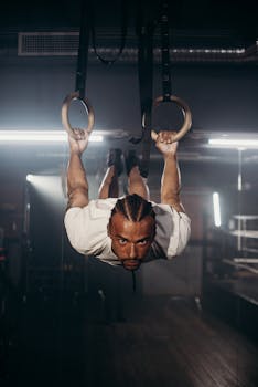 A focused athlete exercises on gymnastic rings indoors, showcasing strength and determination.