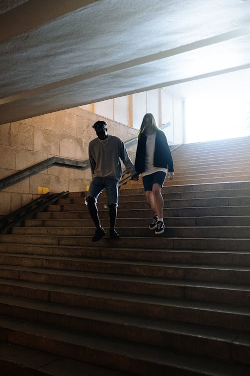 Man in Black Jacket and Brown Pants Walking Down the Stairs