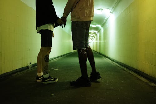 Man in Black Jacket and Blue Denim Jeans Walking on Hallway