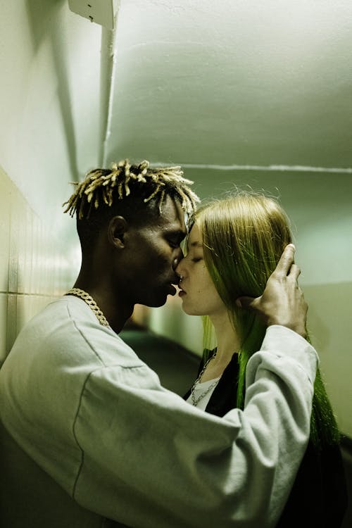 Man and Woman Kissing Near Green Wall